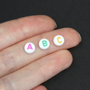 Flat round plastic white beads with coloured mix of letters 